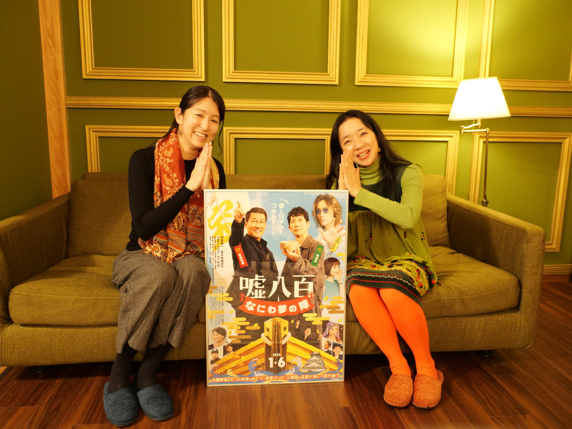 「嘘八百 なにわ夢の陣」のポスターを挟んでおはどう、ございますのポーズをする今井雅子さんと山上庄子