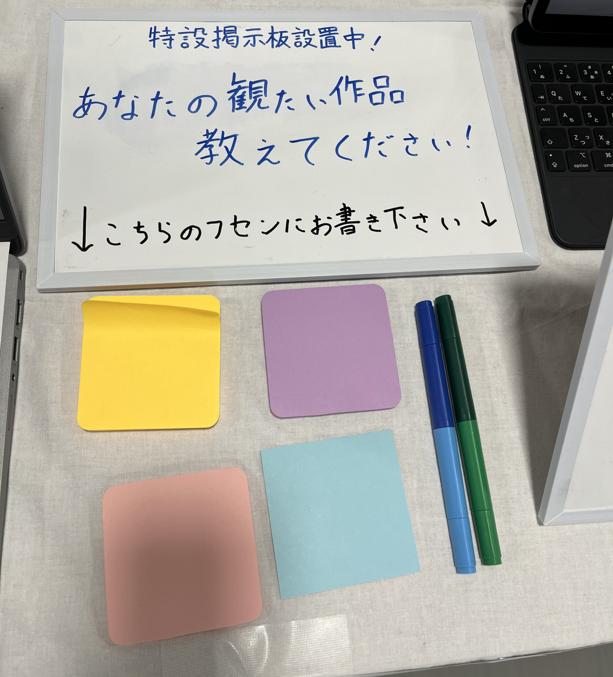 特設掲示板の様子その1。「あなたの観たい作品　教えてください!」という掲示の下に、回答用のペンと付箋がおいてある。