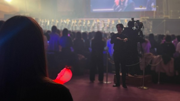 手話通訳の様子。通路のステージ側に手話通訳者が立っており、立席しても手話通訳が見やすい位置関係になっている。